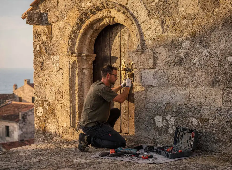 Serrurier professionnel installant une serrure sur une porte ancienne en pierre à Perpignan 66.